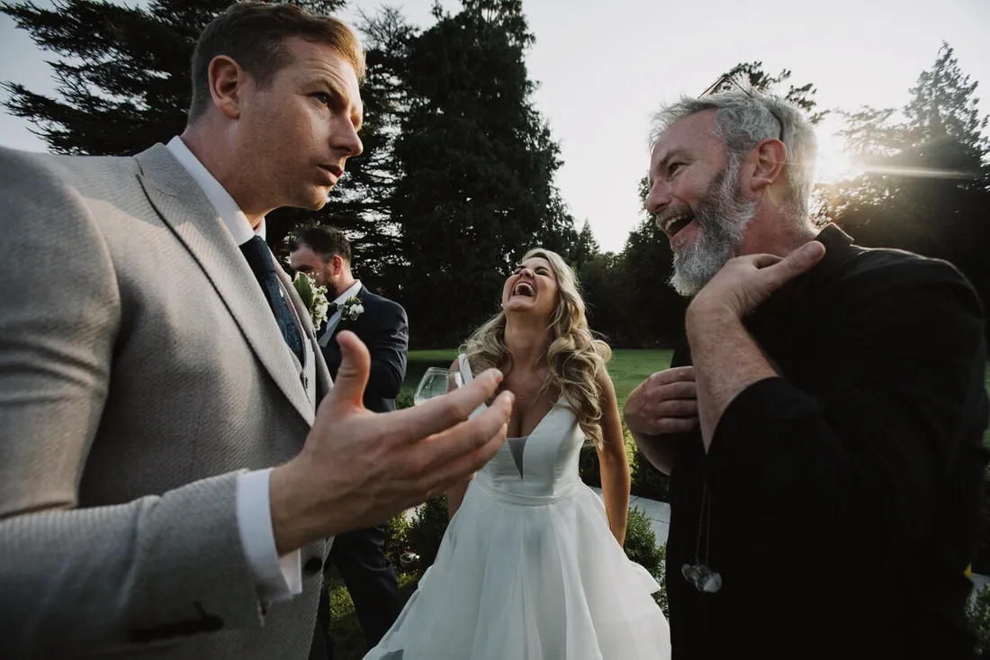 Gary talking with a guest while the bride laughs in the background