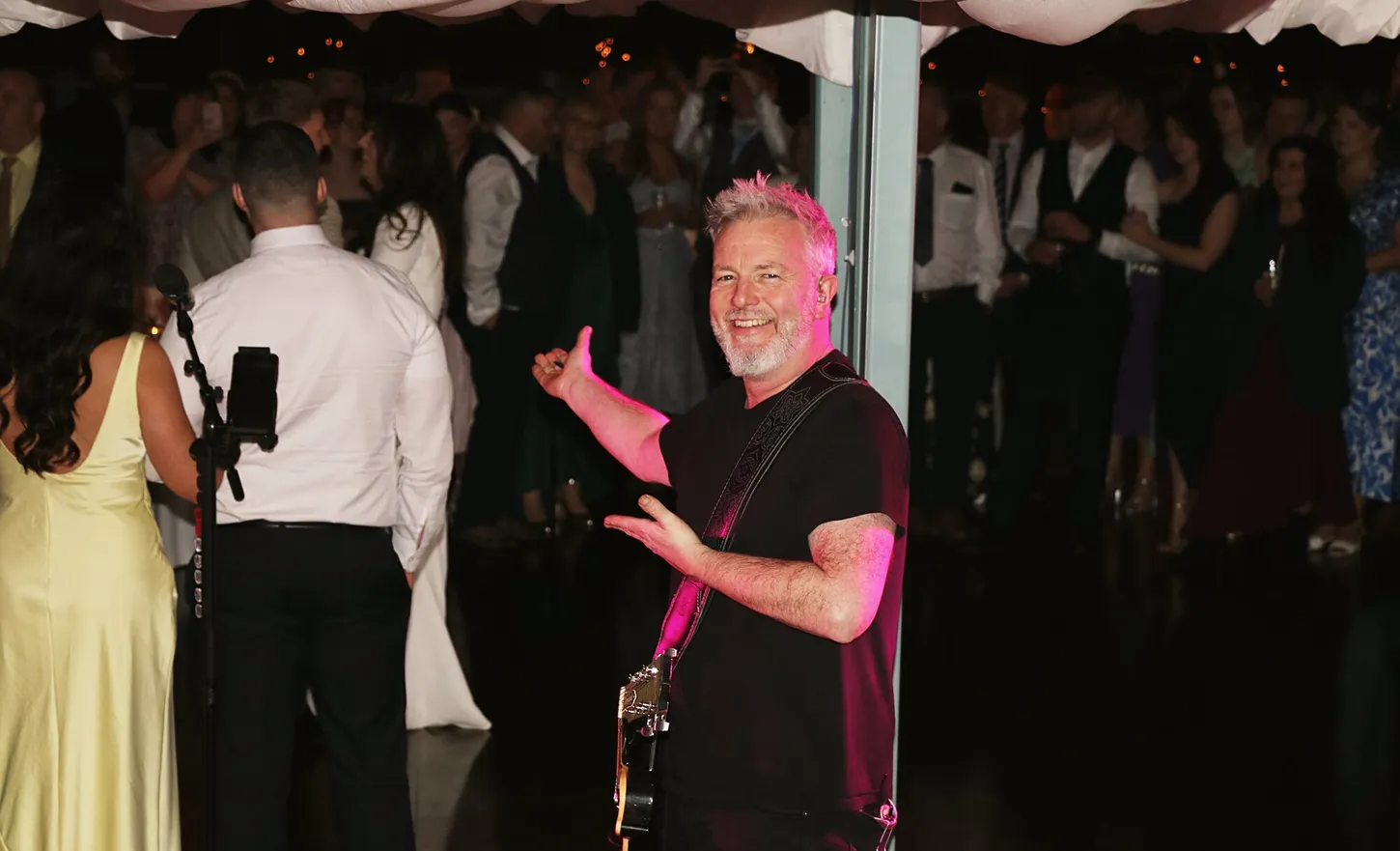 Gary grinning mid-song with a packed wedding dancefloor behind him